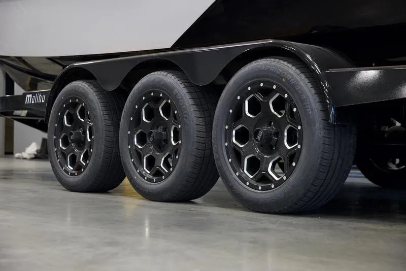 Slide: The Image of 2025 Malibu 25 LSV trailer with black alloy wheels, triple axle design. - 7