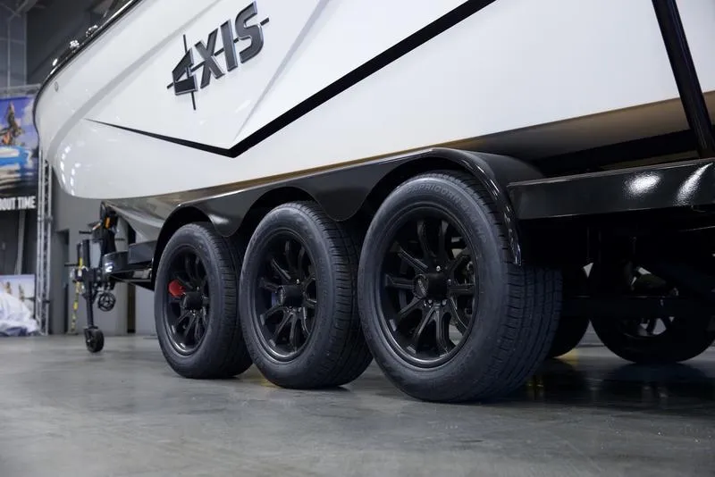 Slide: The Image of 2025 Axis T250 boat on triple-axle trailer with black wheels in a showroom. - 7