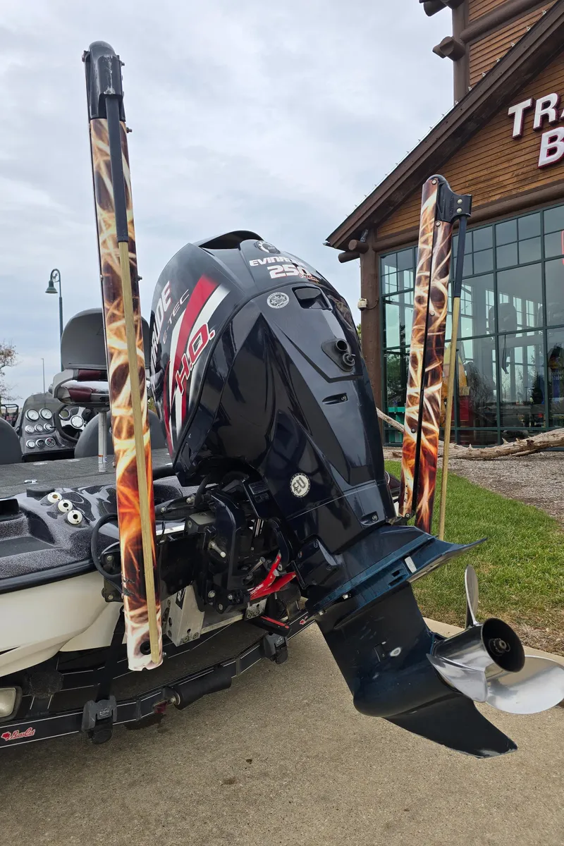 Slide: The Image of 2010 Bass Cat Cougar FTD boat with powerful outboard motor, parked near a building. - 2