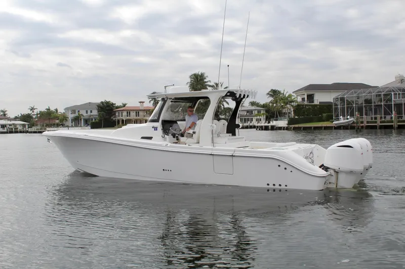 Slide: The Image of 2019 Edgewater 370CC boat cruising on calm waters near waterfront homes. - 1