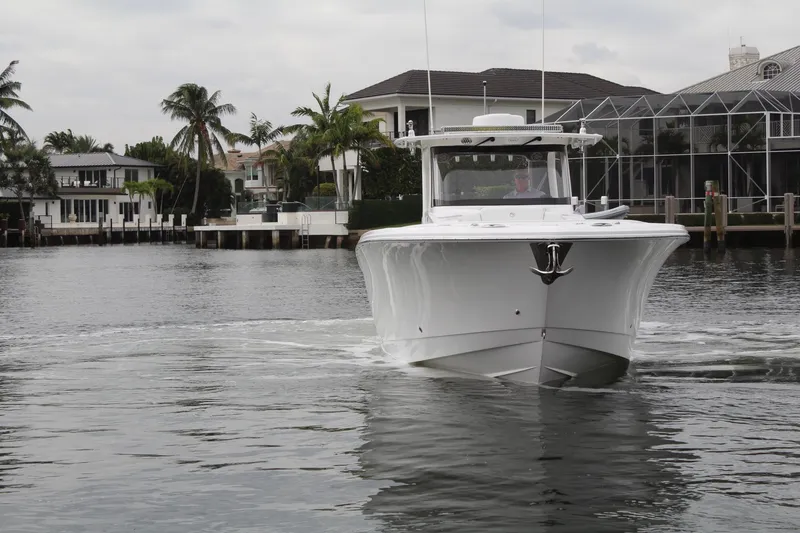 Slide: The Image of 2019 Edgewater 370CC boat cruising in a scenic waterfront area. - 10