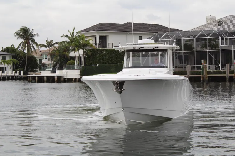 Slide: The Image of 2019 Edgewater 370CC boat cruising near waterfront homes. - 11