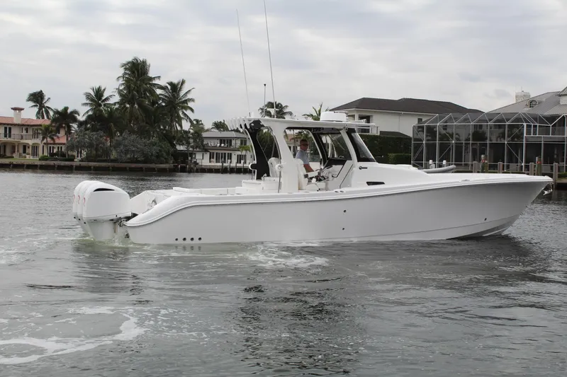 Slide: The Image of 2019 Edgewater 370CC boat cruising on a calm waterfront with palm trees. - 12