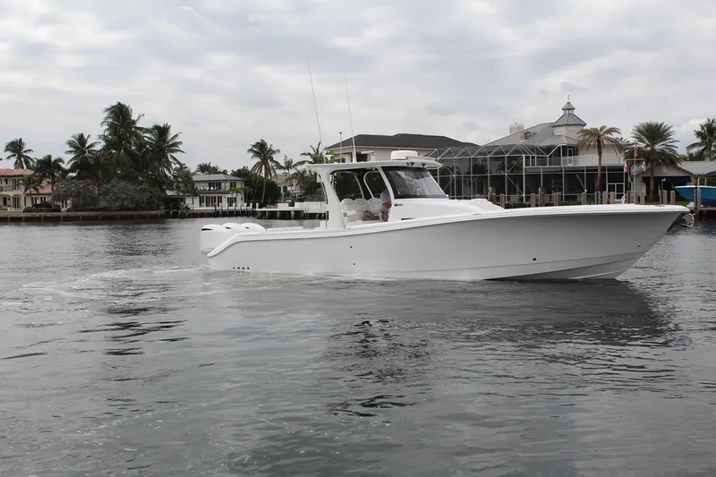 Slide: The Image of 2019 Edgewater 370CC boat cruising on a calm waterfront with palm trees. - 13