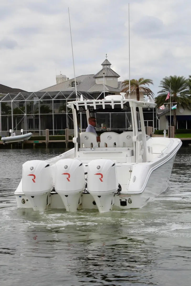 Slide: The Image of 2019 Edgewater 370CC boat with triple outboard engines on a calm waterway. - 14
