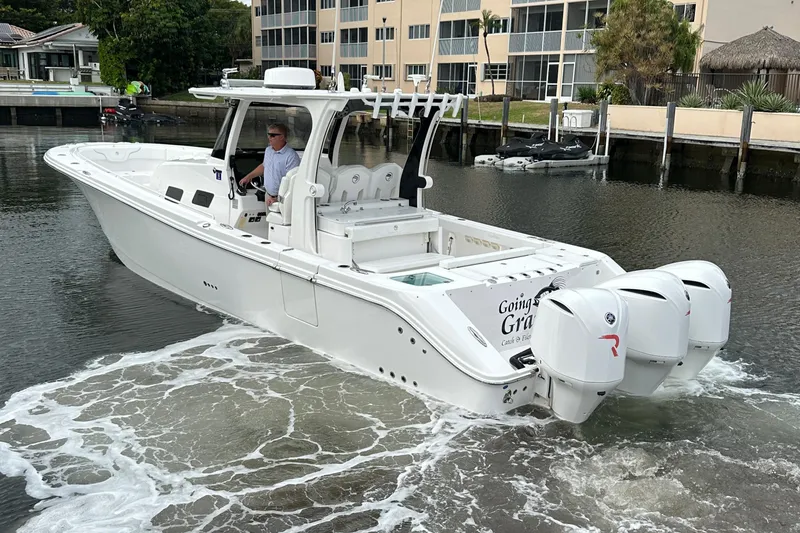 Slide: The Image of 2019 Edgewater 370CC boat with triple engines cruising in a marina. - 7