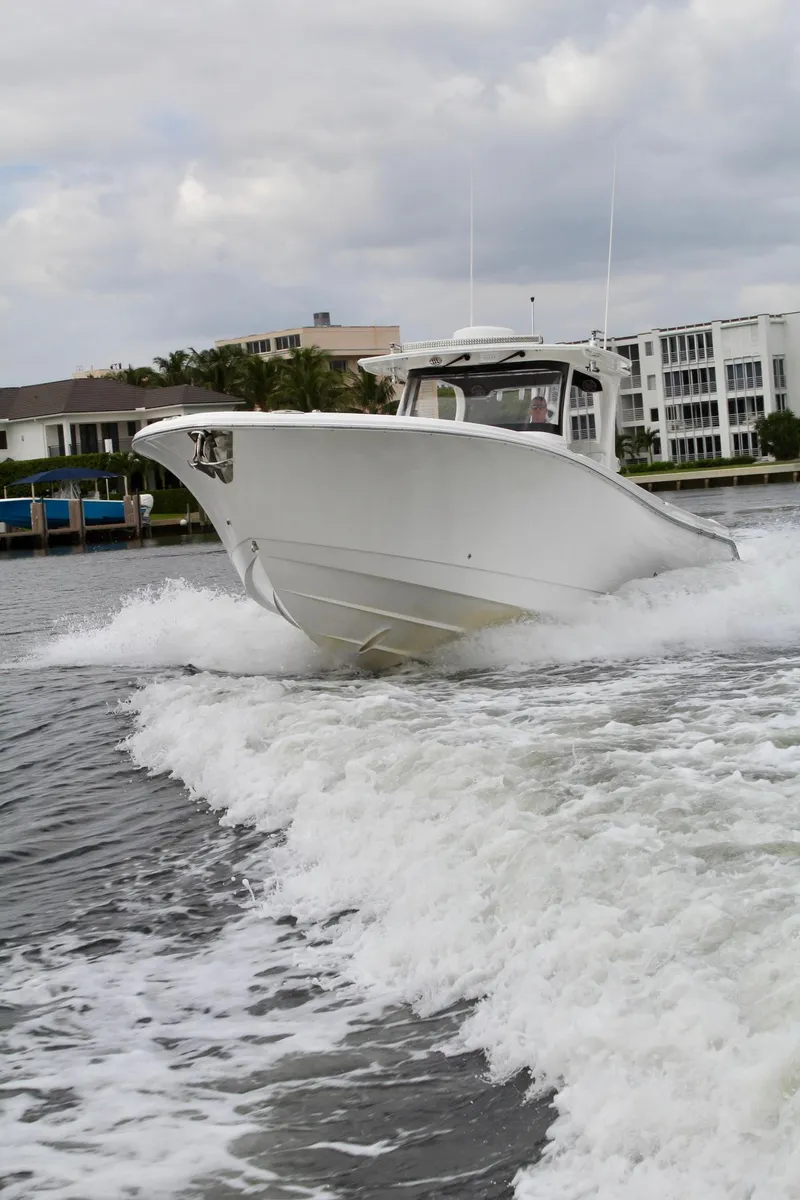 Slide: The Image of 2019 Edgewater 370CC boat cruising on water near waterfront buildings. - 9