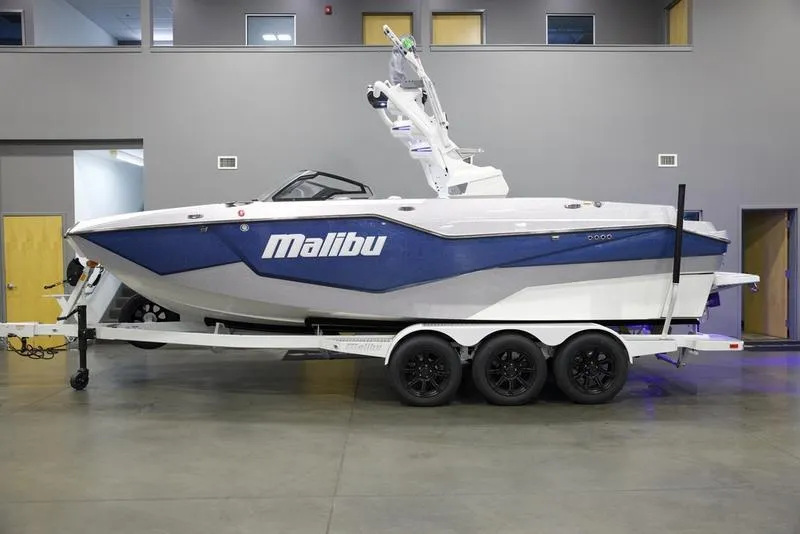 Slide: The Image of 2025 Malibu M242 boat on trailer in showroom. - 1