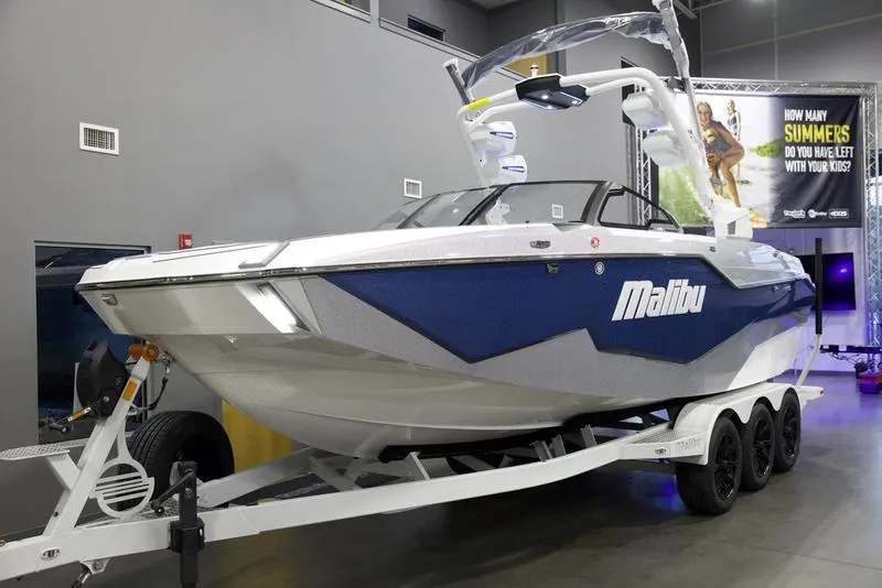 Slide: The Image of 2025 Malibu M242 boat on trailer in showroom, featuring sleek design and modern features. - 3