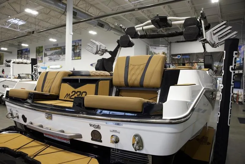 Slide: The Image of 2025 Malibu M230 boat interior with tan seats in a showroom setting. - 13