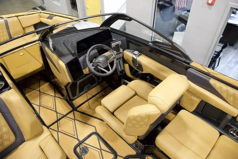 Slide: The Image of 2025 Malibu M230 boat interior with luxurious tan seating and modern dashboard design. - 15