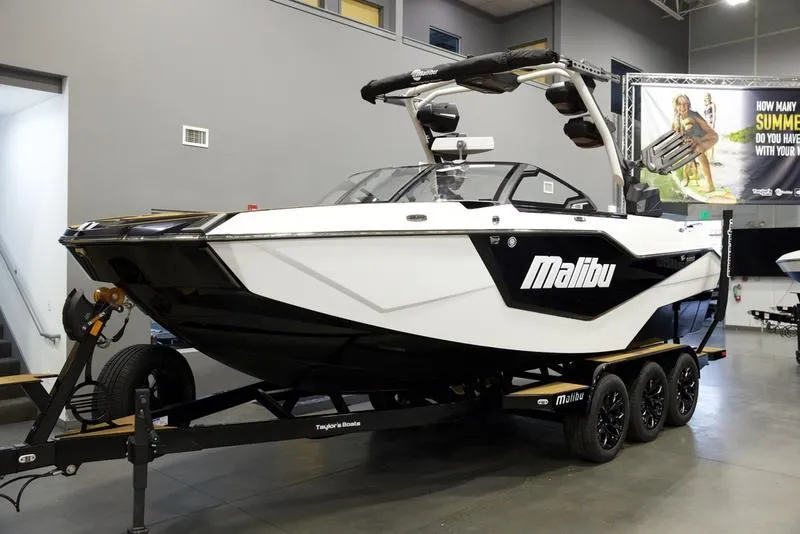 Slide: The Image of 2025 Malibu M230 boat on trailer in showroom, featuring sleek design and modern features. - 3