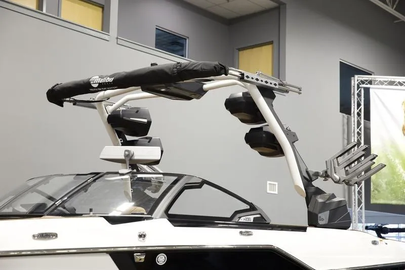 Slide: The Image of 2025 Malibu M230 boat with wakeboard tower and speakers in showroom. - 7