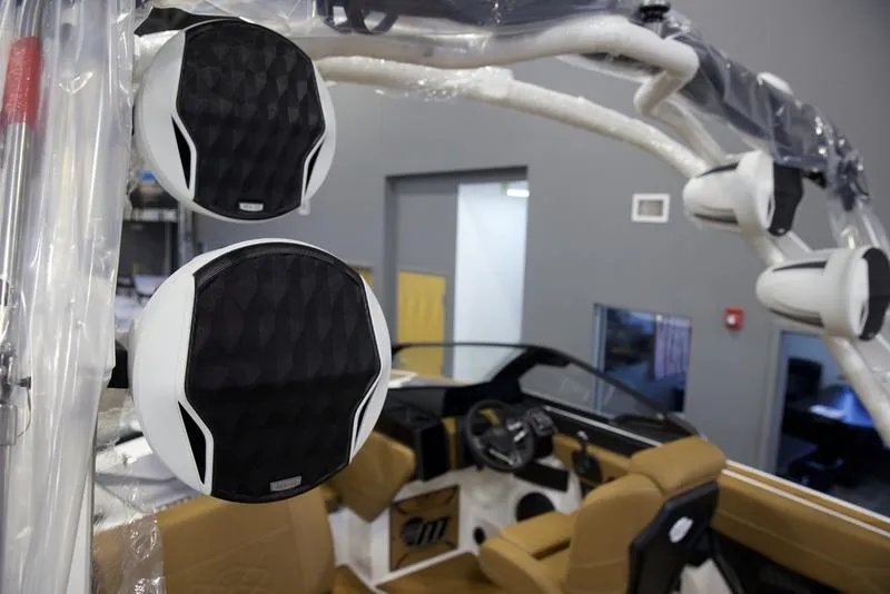 Slide: The Image of 2025 Malibu 23 LSV boat interior with premium audio speakers and tan seating. - 11