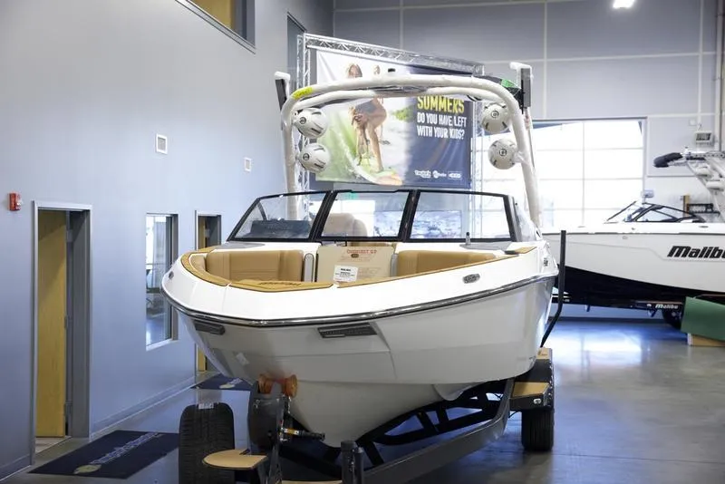 Slide: The Image of 2025 Malibu 23 LSV boat displayed indoors on a trailer. - 8