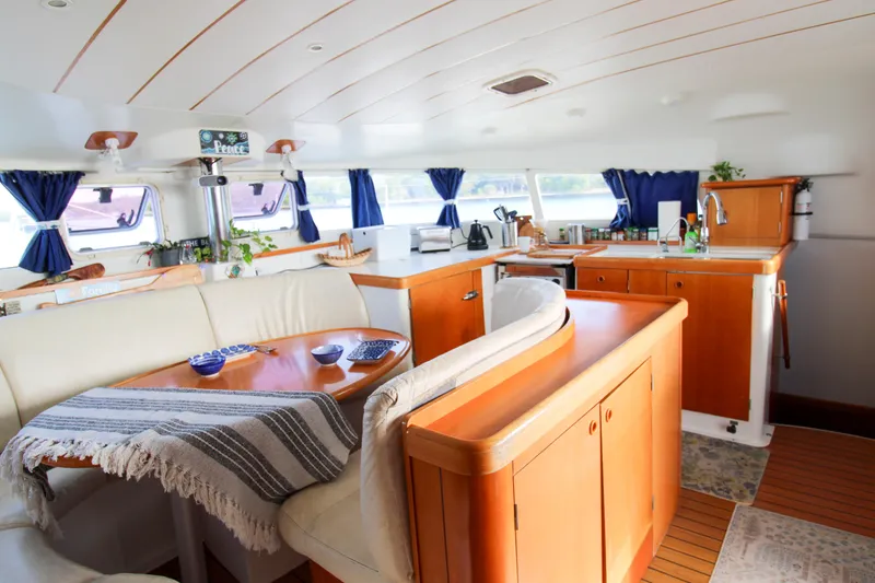 Slide: The Image of Interior of 2002 Lagoon 410 catamaran with cozy seating and kitchen area. - 14