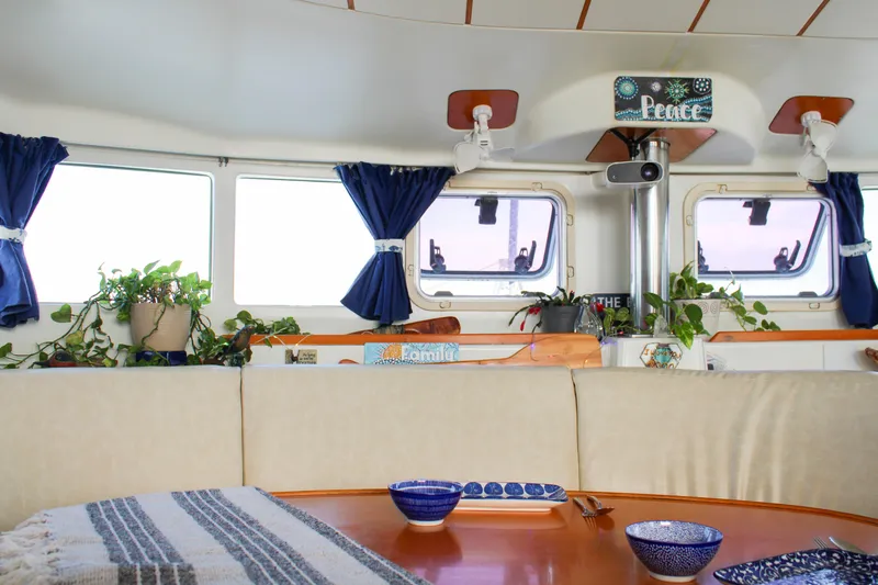 Slide: The Image of Interior of 2002 Lagoon 410 catamaran with cozy seating, plants, and nautical decor. - 16