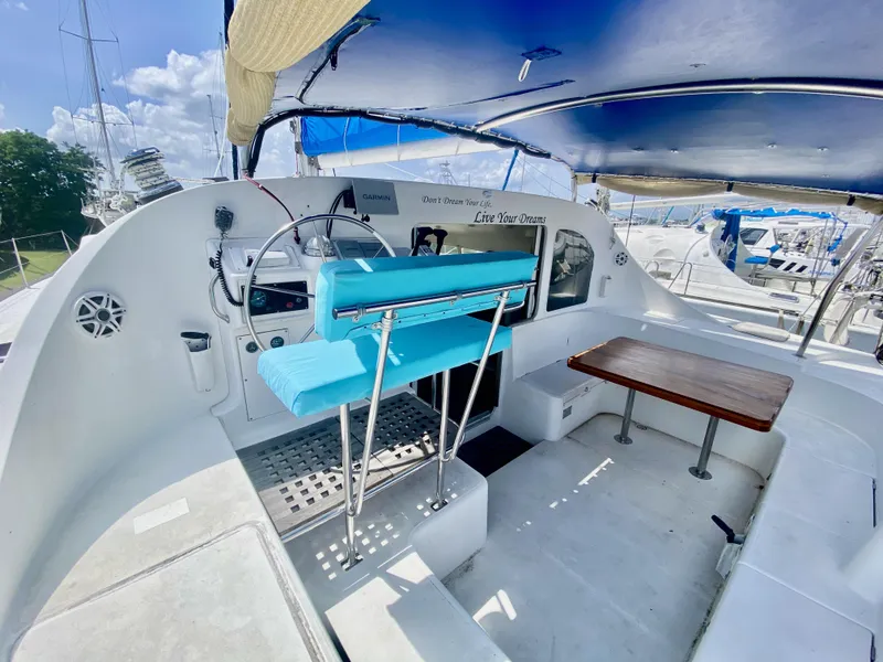 Slide: The Image of Cockpit of 2002 Lagoon 410 catamaran with blue seating and wooden table. - 6