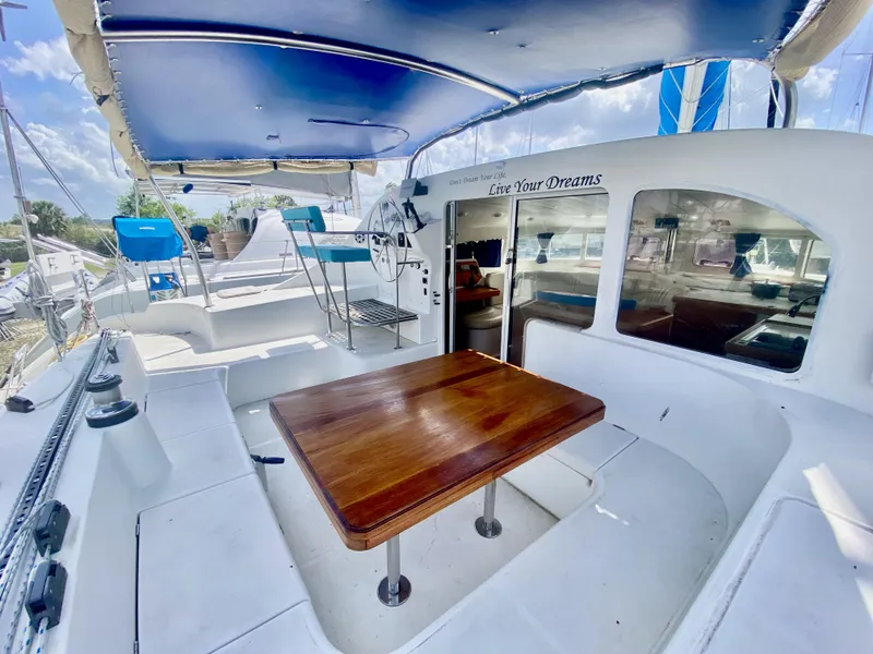 Slide: The Image of 2002 Lagoon 410 catamaran with spacious deck and wooden table, under a blue canopy. - 7