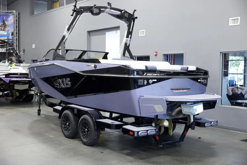 Slide: The Image of 2025 Axis T220 boat on trailer in showroom, sleek black and gray design. - 4