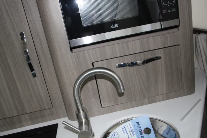 Slide: The Image of Modern kitchen area in 2022 Regal 28 Express boat with microwave and faucet. - 36