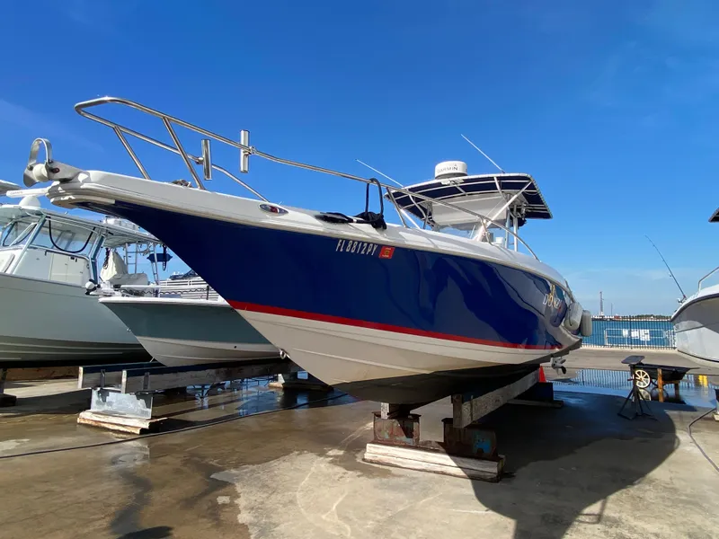 Slide: The Image of 2000 Donzi 35 ZF Open boat on dry dock, blue hull, clear sky background. - 11