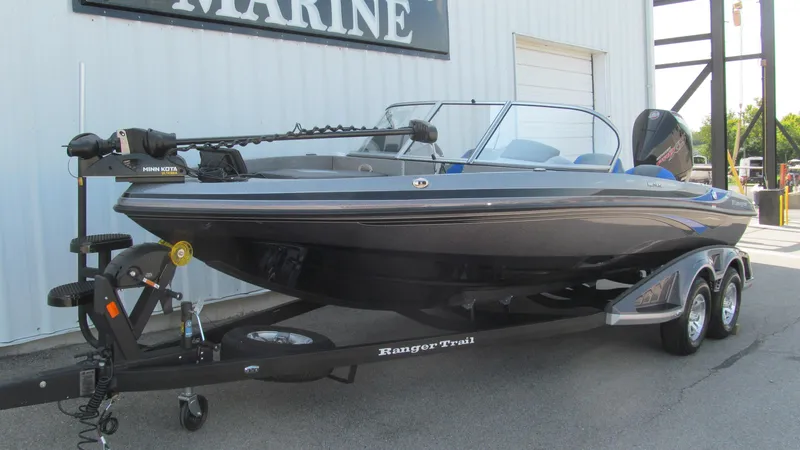 Slide: The Image of 2025 Ranger 212LS boat on trailer, parked outside a marine shop. - 2