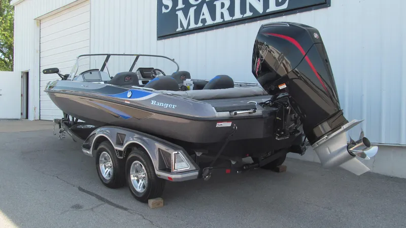 Slide: The Image of 2025 Ranger 212LS boat on trailer outside marine store. - 3
