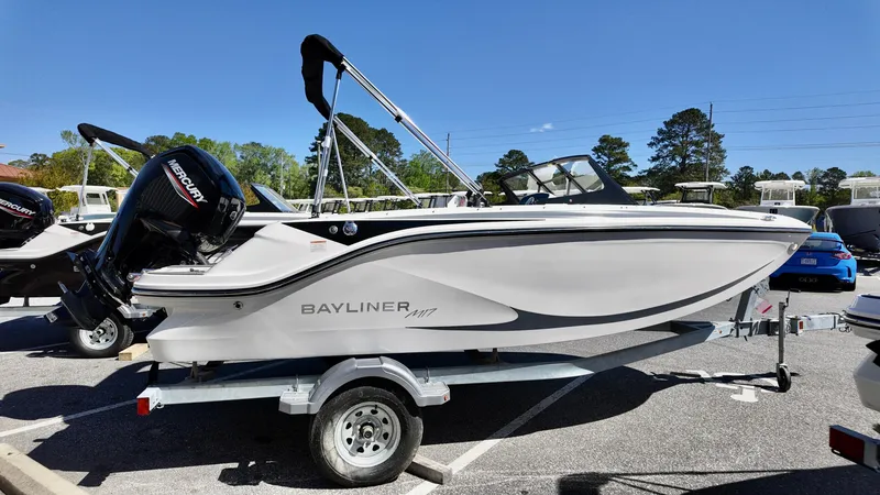 Slide: The Image of 2025 Bayliner M17 boat on trailer, parked outdoors under clear blue sky. - 2