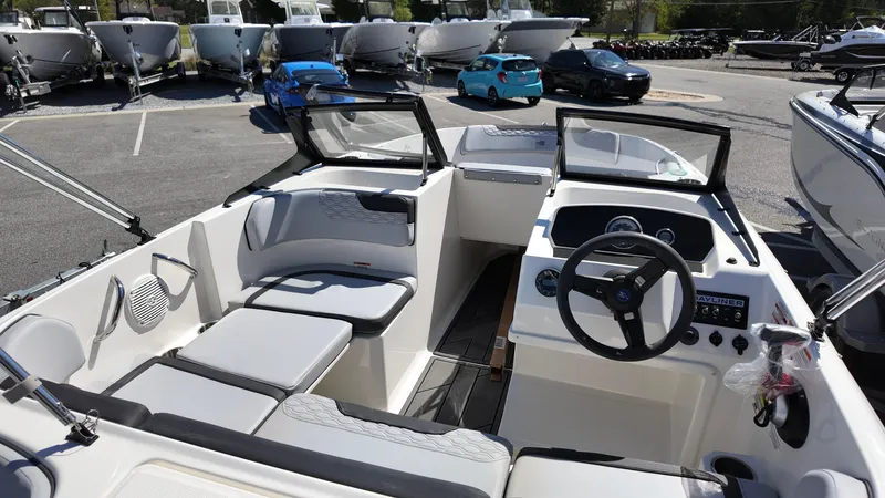 Slide: The Image of 2025 Bayliner M17 boat interior with steering wheel and seating, parked in a marina. - 9