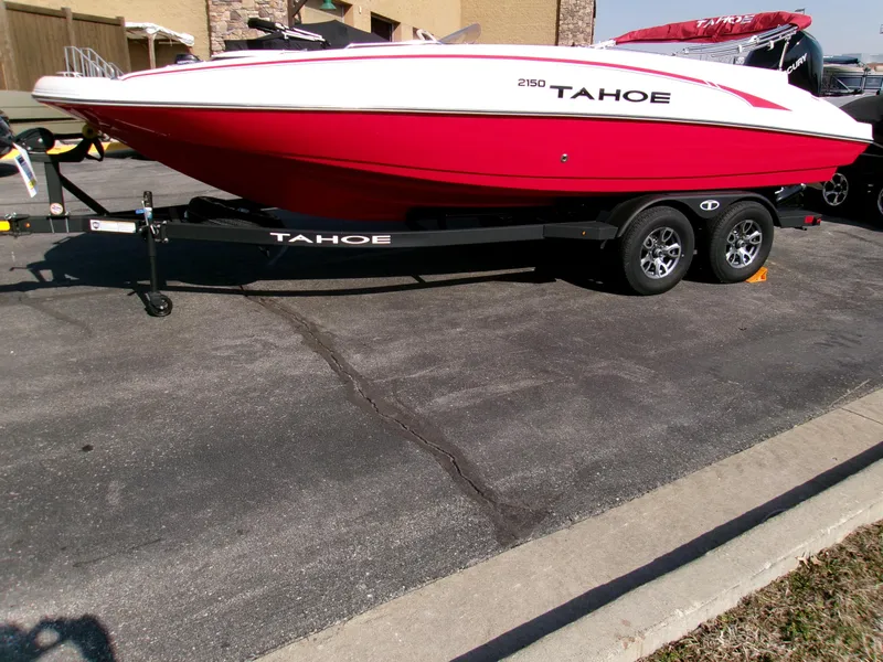 Slide: The Image of 2025 Tahoe 2150 boat in red and white on a trailer, parked outdoors. - 2