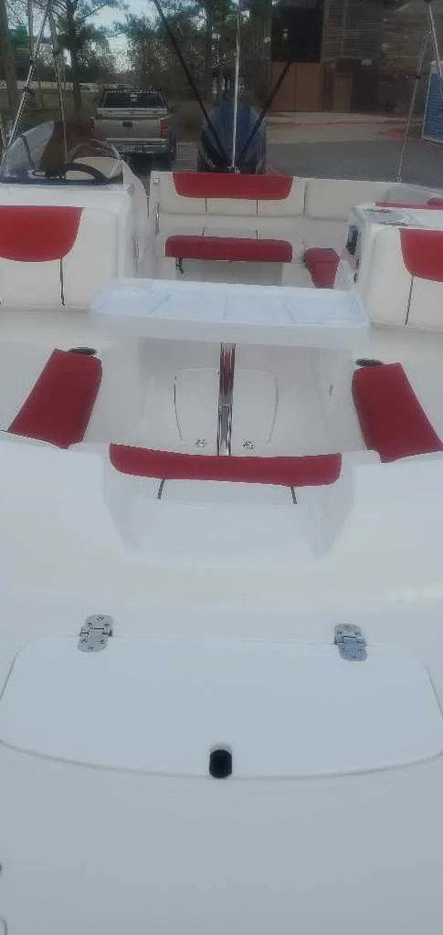 Slide: The Image of 2025 Tahoe 2150 boat with red hull and canopy in parking lot, Louisiana Sportsman's Paradise backdrop. - 2