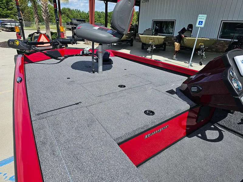 Slide: The Image of 2025 Ranger RT178C boat with red deck and seating, parked outdoors. - 12