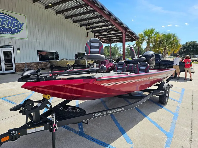 Slide: The Image of 2025 Ranger RT178C boat in red, parked outside a dealership under a metal awning. - 2