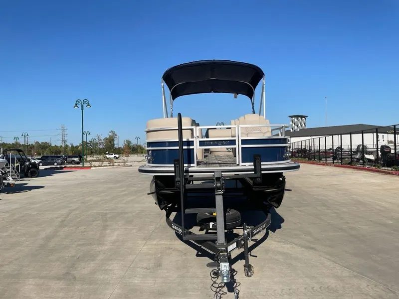 Slide: The Image of 2025 Ranger Reata 220FC pontoon boat on trailer, parked outdoors under clear blue sky. - 2