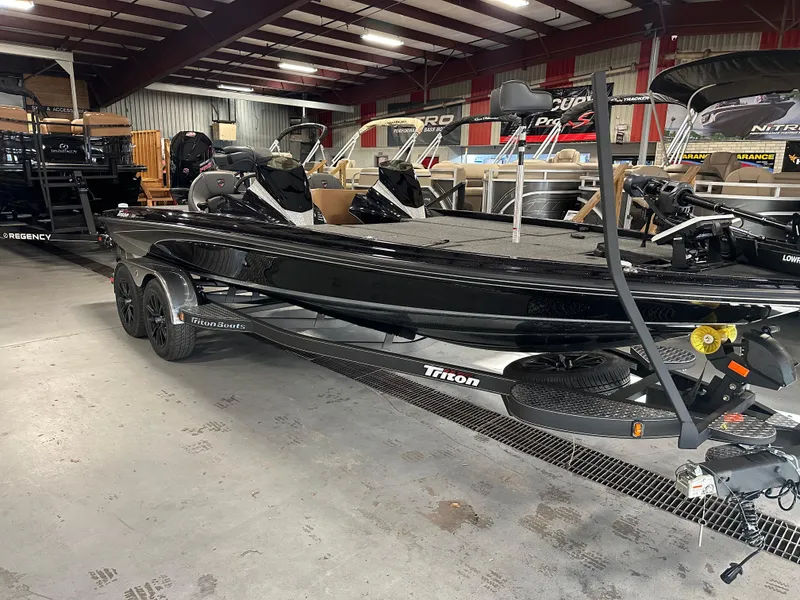 Slide: The Image of 2025 Triton 21XP Patriot boat in showroom, sleek black design, on trailer. - 1
