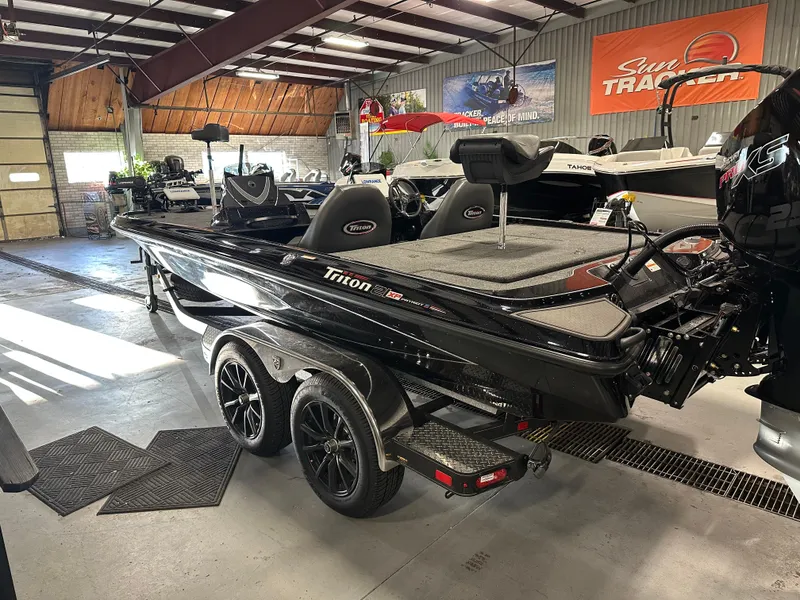 Slide: The Image of 2025 Triton 21XP Patriot boat in showroom, black exterior, dual axle trailer, indoor lighting. - 6