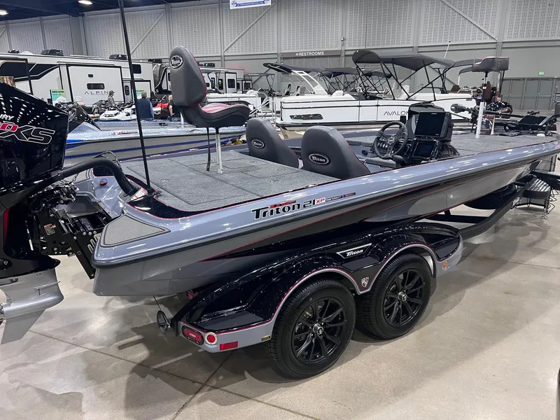 Slide: The Image of 2025 Triton 21XP Patriot boat on display, featuring sleek design and dual axle trailer. - 1
