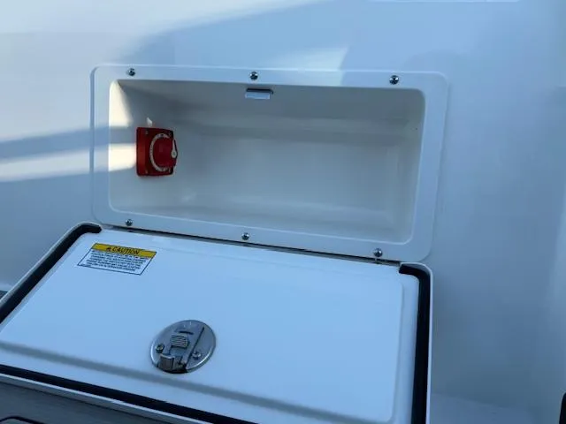 Slide: The Image of Sea Ray SPX 230 2025 boat storage compartment with latch and red switch. - 11