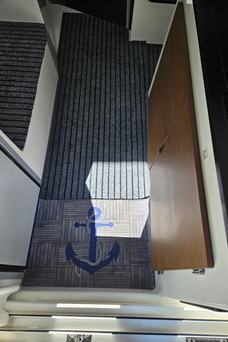 Slide: The Image of 2023 Jeanneau NC795 interior with anchor-themed carpet and wooden door. - 33