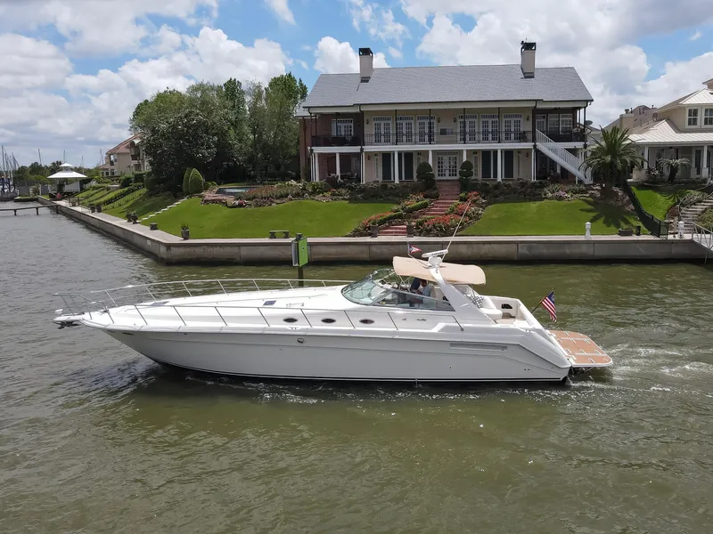 The Image of Sea Ray 500 Sundancer 1996 yacht cruising near waterfront homes. - 0