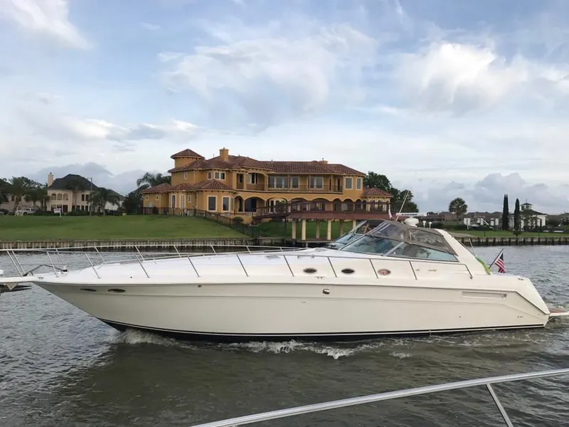Slide: The Image of 1996 Sea Ray 500 Sundancer yacht cruising near luxurious waterfront mansion. - 10