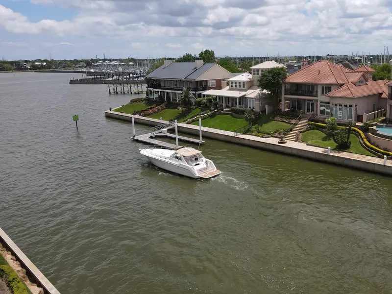 Slide: The Image of 1996 Sea Ray 500 Sundancer cruising near waterfront homes on a sunny day. - 13