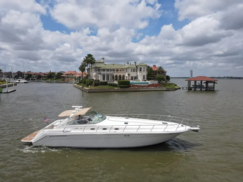 Slide: The Image of 1996 Sea Ray 500 Sundancer cruising near luxurious waterfront homes under a cloudy sky. - 3