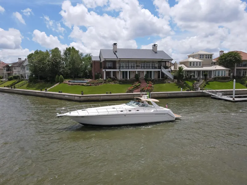 Slide: The Image of 1996 Sea Ray 500 Sundancer yacht cruising near waterfront homes under a cloudy sky. - 4
