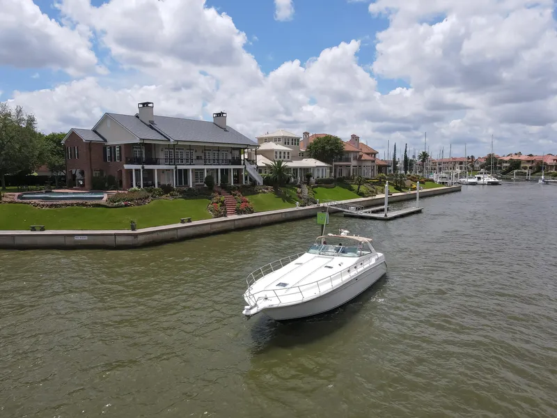 Slide: The Image of 1996 Sea Ray 500 Sundancer cruising near waterfront homes under a cloudy sky. - 5