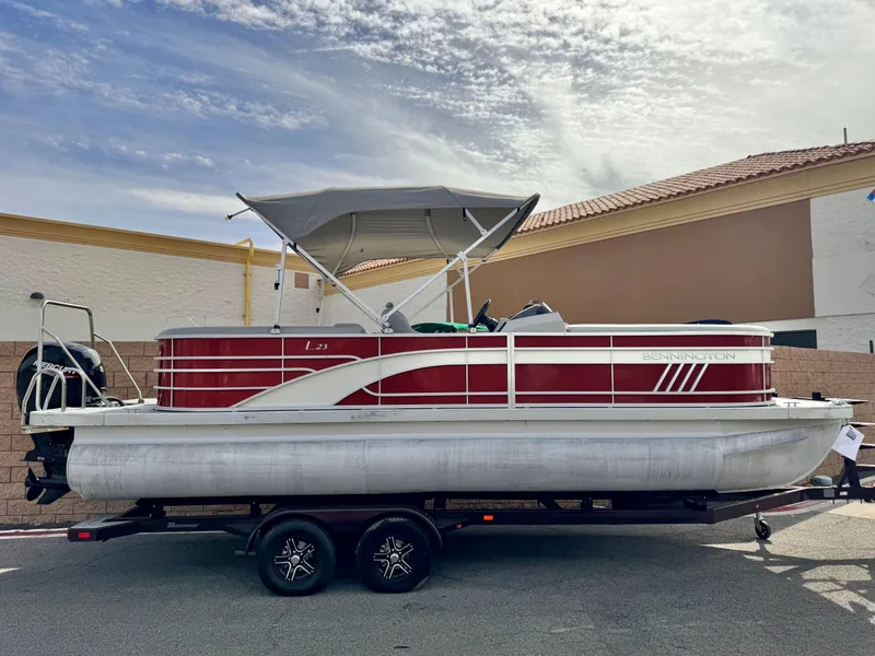 The Image of 2021 Bennington 23 LS RSD pontoon boat on trailer, red and white design, parked outdoors. - 0