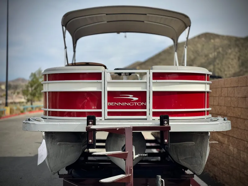 Slide: The Image of 2021 Bennington 23 LS RSD pontoon boat with red exterior, parked on a trailer. - 2