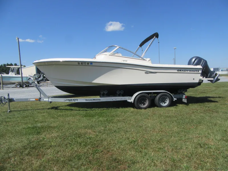 Slide: The Image of 2017 Grady-White 225 Freedom boat on trailer, parked on grass under clear blue sky. - 3