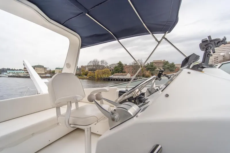 Slide: The Image of Bayliner 4788 Pilot House Motoryacht 2000 helm with blue canopy and waterfront view. - 45
